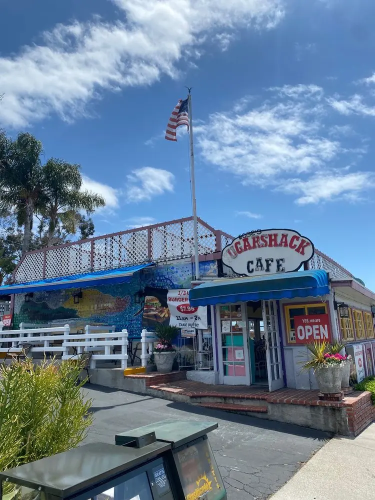 Rose's Sugarshack Cafe exterior with an American flag, palm trees and vivid blue sky on a sunny San Clemente day