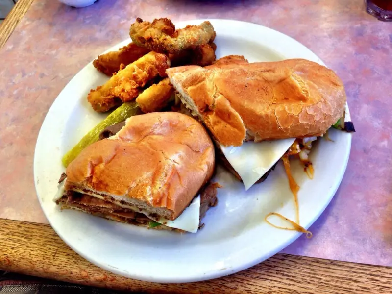 Beef and provolone sandwich on a toasted roll served with a side of breaded fried zucchini