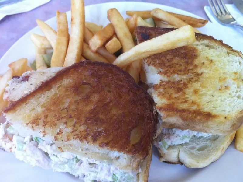 Grilled tuna melt on golden toasted bread cut in half, served with a pile of French fries