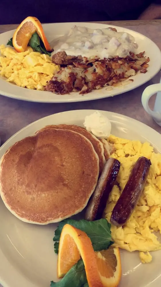 Two breakfast plates of pancakes with sausage and chicken fried steak with country gravy