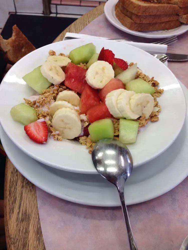 Yogurt and granola bowl piled with banana, melon and strawberries