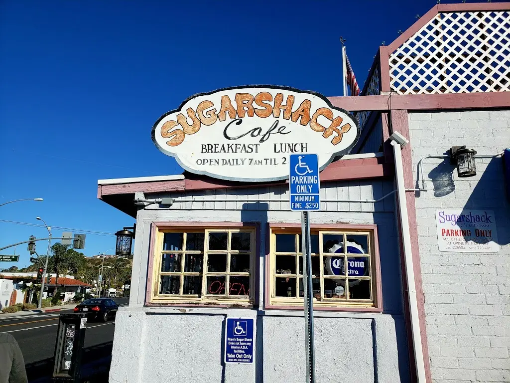 Corner exterior of Sugarshack Cafe with hand-painted sign and windows against a deep blue sky